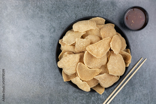 Kerupuk udang - traditional indonesian shrimp crackers on a gray background with sweet chili sauce. Shrimp chips or crackers. Thai snacks. Top view, copy space.