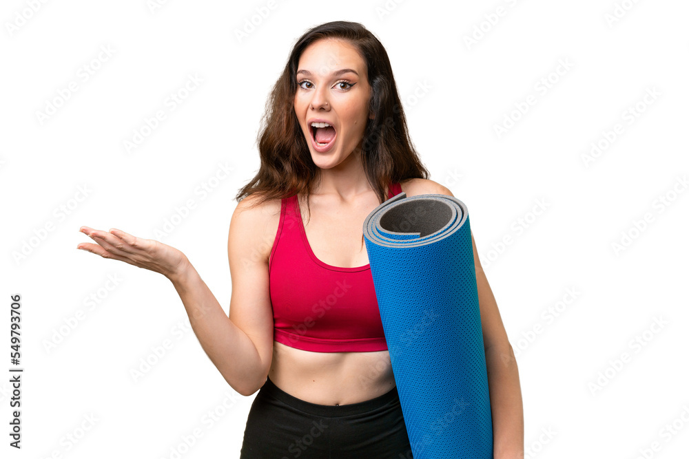 Young sport woman going to yoga classes while holding a mat over isolated background with shocked facial expression Young sport woman going to yoga classes while holding a mat over isolated background with shocked facial expression