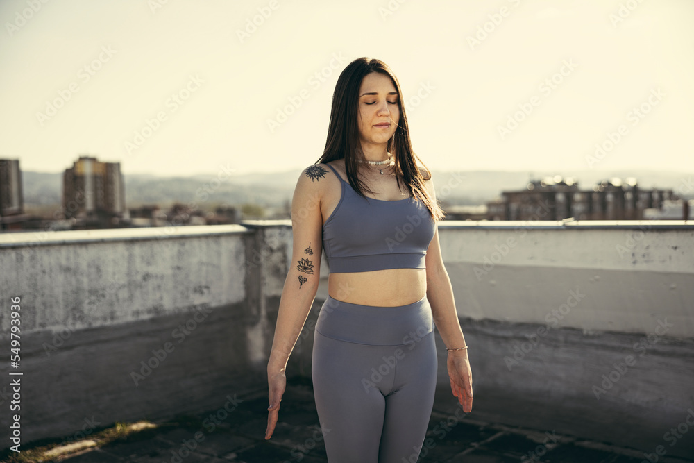 Fototapeta premium Woman Doing Yoga Outdoors On A Rooftop Terrace