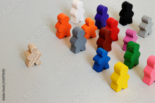 Bild auf Leinwand Wooden figures: one colorless person walking alone and colorful people standing together