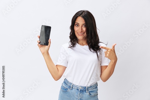 Woman blogger with a phone in her hands photo content, video call, selfie smile with teeth in a white t-shirt on a white background, copy space, emotions and gestures signals © SHOTPRIME STUDIO