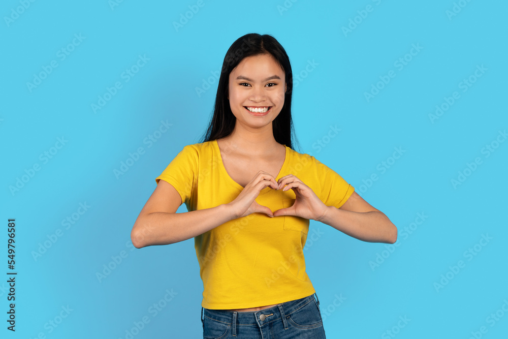 Happy pretty young korean lady in yellow t-shirt show heart sign with hands on chest, looking at camera Happy pretty young korean lady in yellow t-shirt show heart sign with hands on chest, looking at camera