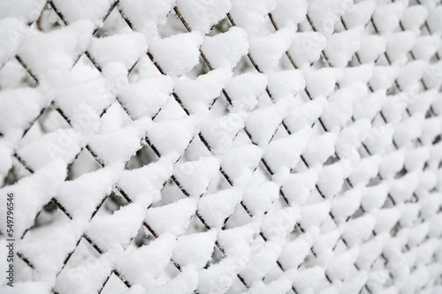 Winter, snowfall. Snow covered metal mesh. Diffused light and selective focus