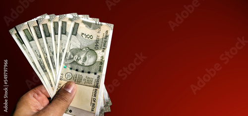 Hand holding five hundred Indian rupee notes against red background photo