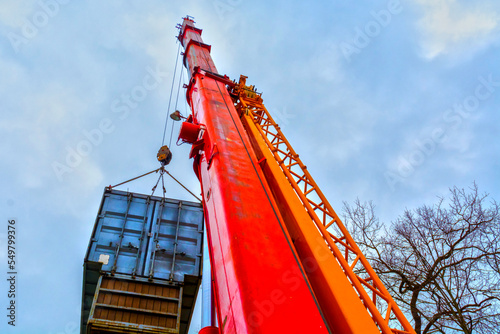 Red crane machine is lifting a container