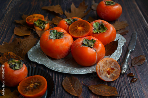 Ripe orange persimmon fruits. fresh persimmon on a metal dish on a wooden table