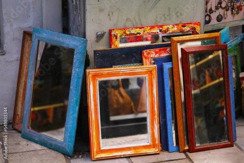 Colored vintage mirrors stand outside at a flea market