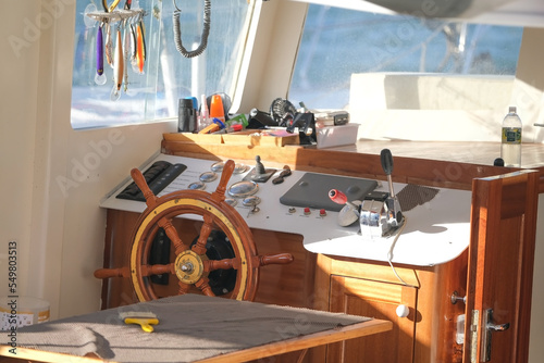 Wooden steering wheel and dashboard inside the yacht