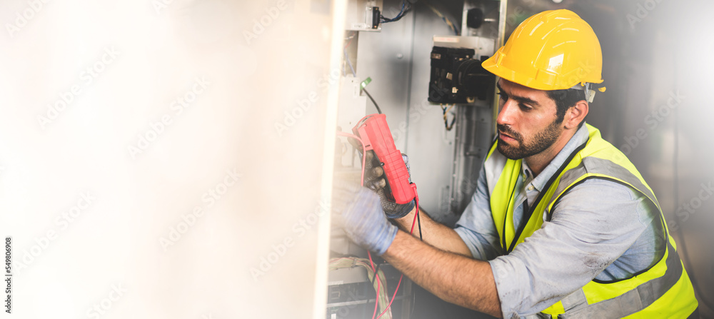 Electrical engineer work tester measuring voltage and current of power electric line in electrical cabinet control for industrial production. Panorama image use for cover design.