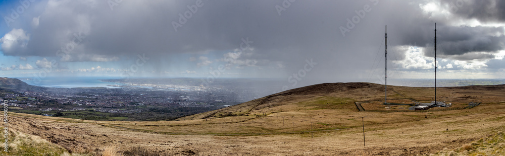 View of Belfast city from the top of Divis and The Black Mountain. Weather contrast of the rain on one side of the mountain and the sun to the other side. Belfast, Norther Ireland, UK View of Belfast city from the top of Divis and The Black Mountain. Weather contrast of the rain on one side of the mountain and the sun to the other side. Belfast, Norther Ireland, UK