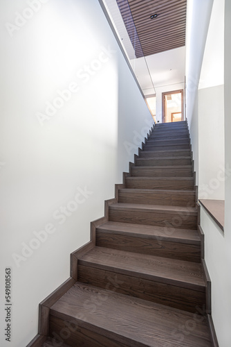 wooden staircase in a luxury house with white walls