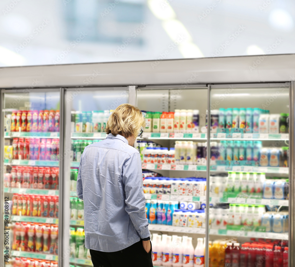  Man choosing frozen food from a supermarket freezer., reading product information