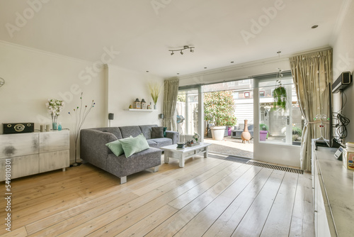 Spacious living room with corner sofa and modern TV set in daylight