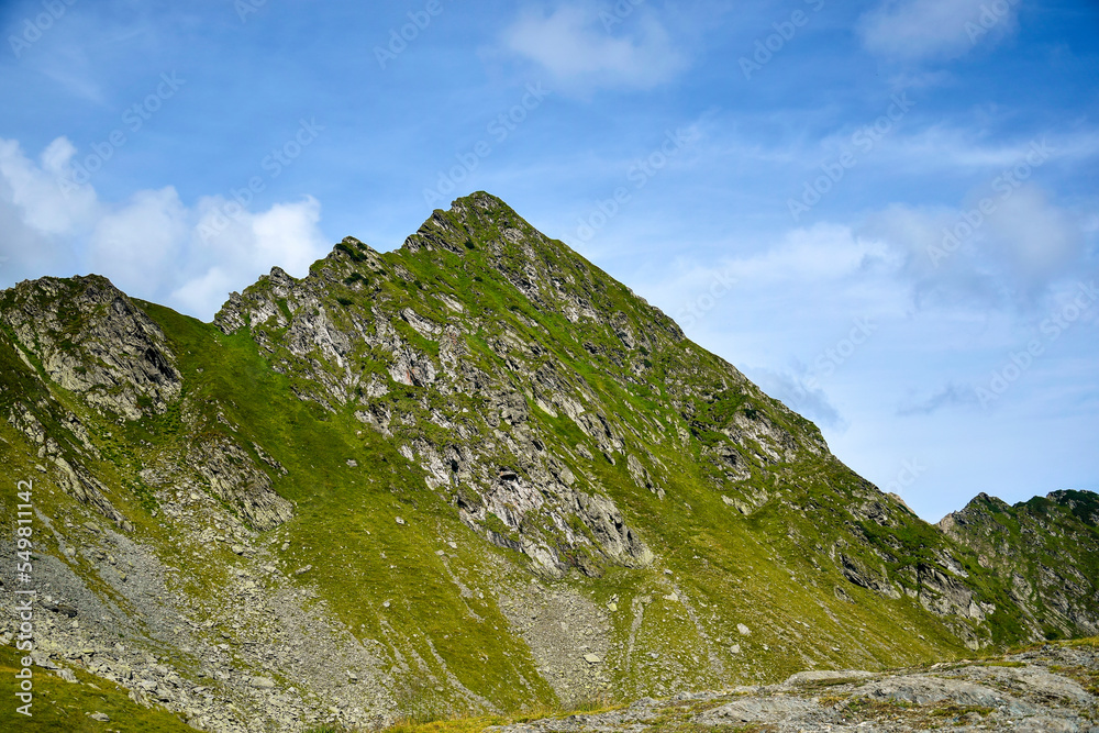 Mountain landscape, peak of mountain range. Close-up. Top of mountain range against blue sky with clouds. Copy space. Selective focus. Mountain landscape, peak of mountain range. Close-up. Top of mountain range against blue sky with clouds. Copy space. Selective focus.