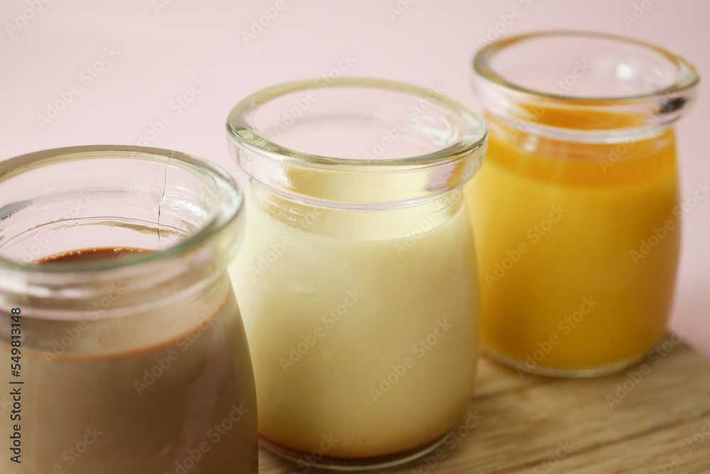 Caramel, chocolate and mango pudding in a glass jar on pink background Caramel, chocolate and mango pudding in a glass jar on pink background