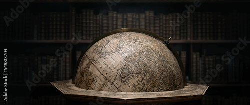 Old geographical globe in cabinet with bookselfs. Science, education, travel, vintage background. History and geography team. Ancience, antique globe on the background of books. photo