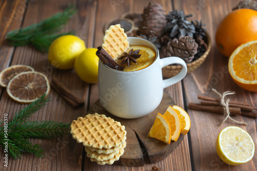 Aromatic tea with orange and spices on a wooden table. Pie, lemons, oranges winter mood.