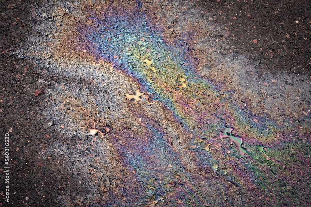 A puddle of spilled gasoline or oil product on the road. Environmental pollution concept