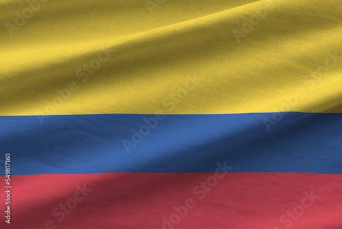 Colombia flag with big folds waving close up under the studio light indoors. The official symbols and colors in banner photo