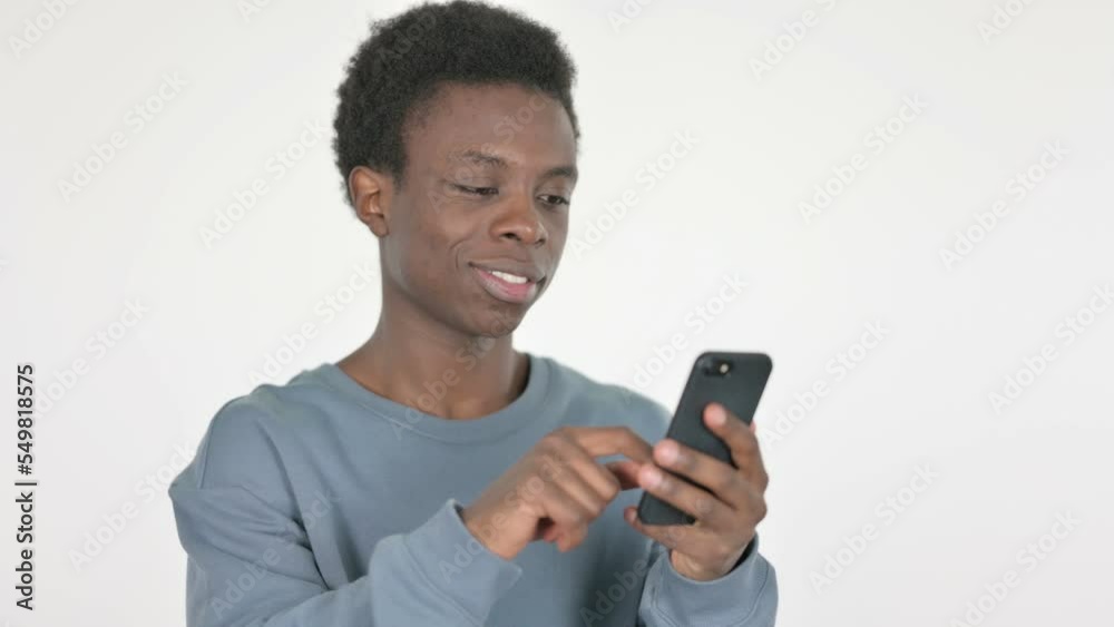 Young African Man Browsing Smartphone on White Background Young African Man Browsing Smartphone on White Background