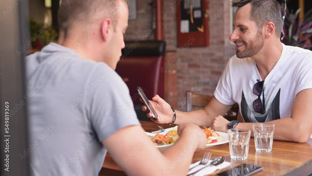 Same sex couple eating at outdoor cafe. Same sex couple eating at outdoor cafe.