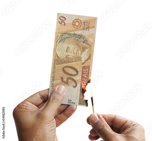 Burning money. Male hand setting a 50 reais bill on fire. Money from Brazil. 3d rendering. Transparente background.