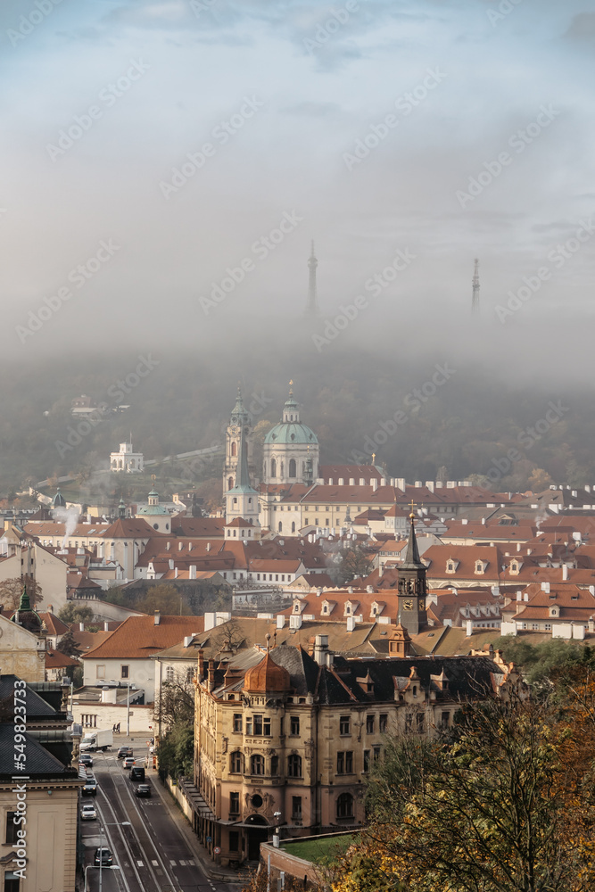 Prague panorama with historical buildings in foggy autumn morning,Czech Republic.View of Church of Saint Nicholas and Petrin Tower in mist.Amazing European cityscape.Travel architecture concept.