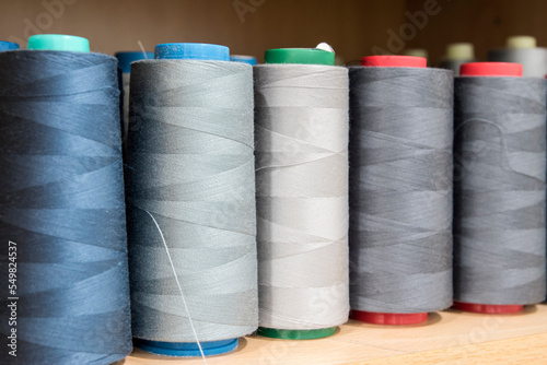 Sewing thread cones of different shade of colors on shelf in sewing studio closeup