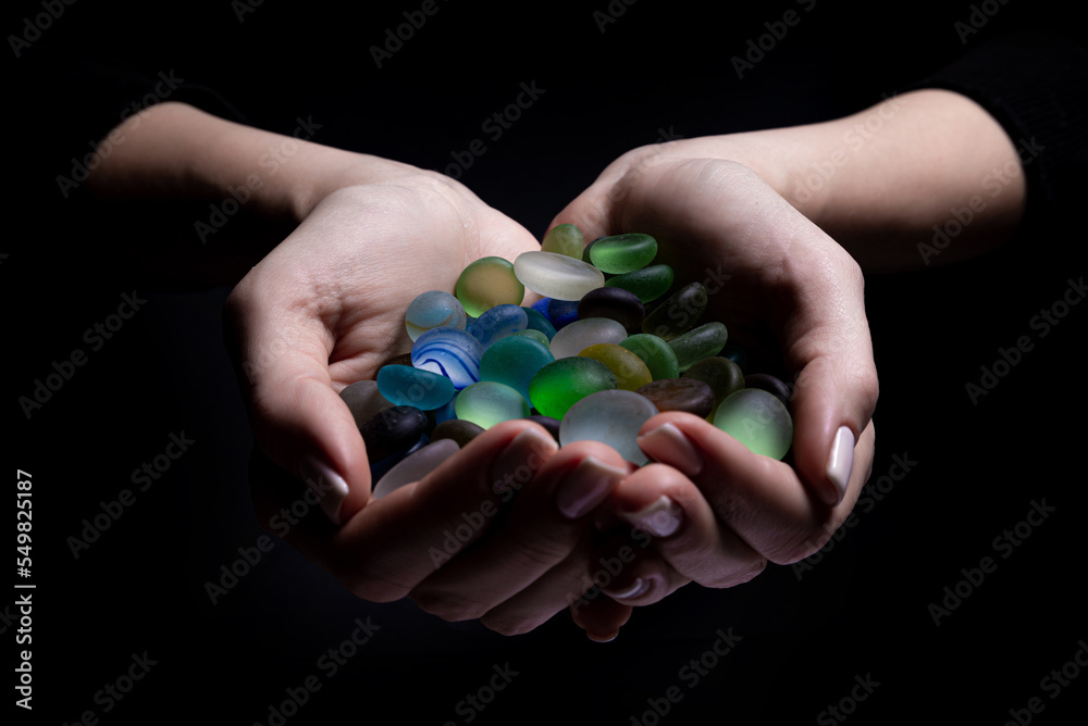 hands with colored stones Young woman is holding a collection of various raw mineral gemstones in her palm isolated on black