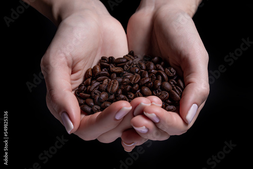 hands with coffee beans Woman hands holding roasted coffee beans (focus on beanz) female hands cupped holding coffee beans, on black