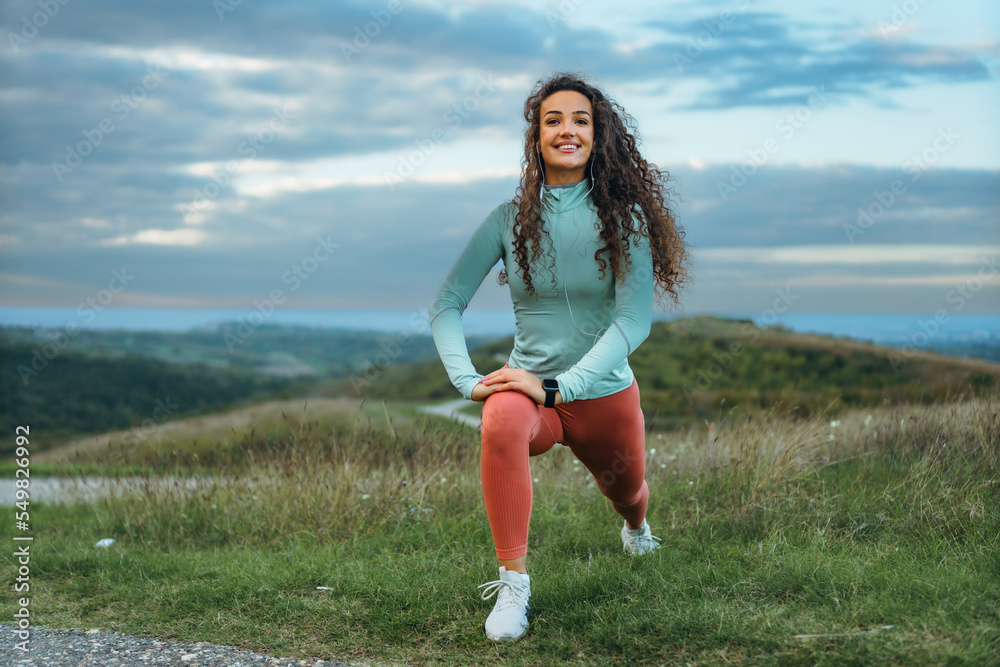 A girl with amazing curls stretching her body and absorbing the breathtaking sceneries around her, listening to music on her smart phone A girl with amazing curls stretching her body and absorbing the breathtaking sceneries around her, listening to music on her smart phone