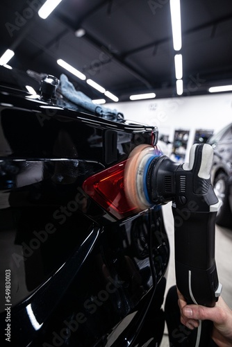Obraz na płótnie car wash or car detailing studio worker polishes the paintwork of a black car w salonie