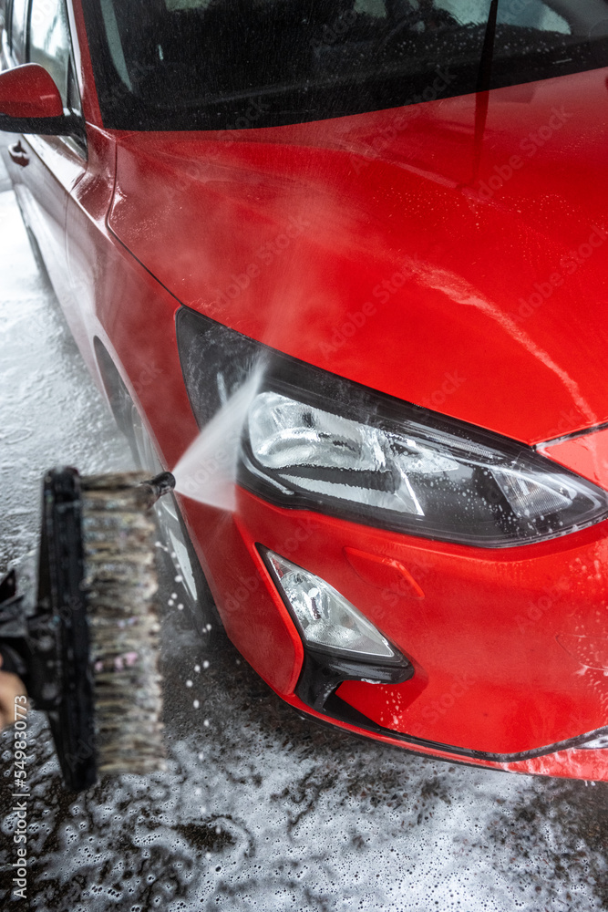 Front lights of a red car being washed.