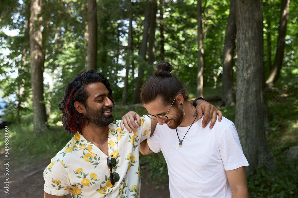 Portrait of male LGBTQ couple in campground laughing Portrait of male LGBTQ couple in campground laughing