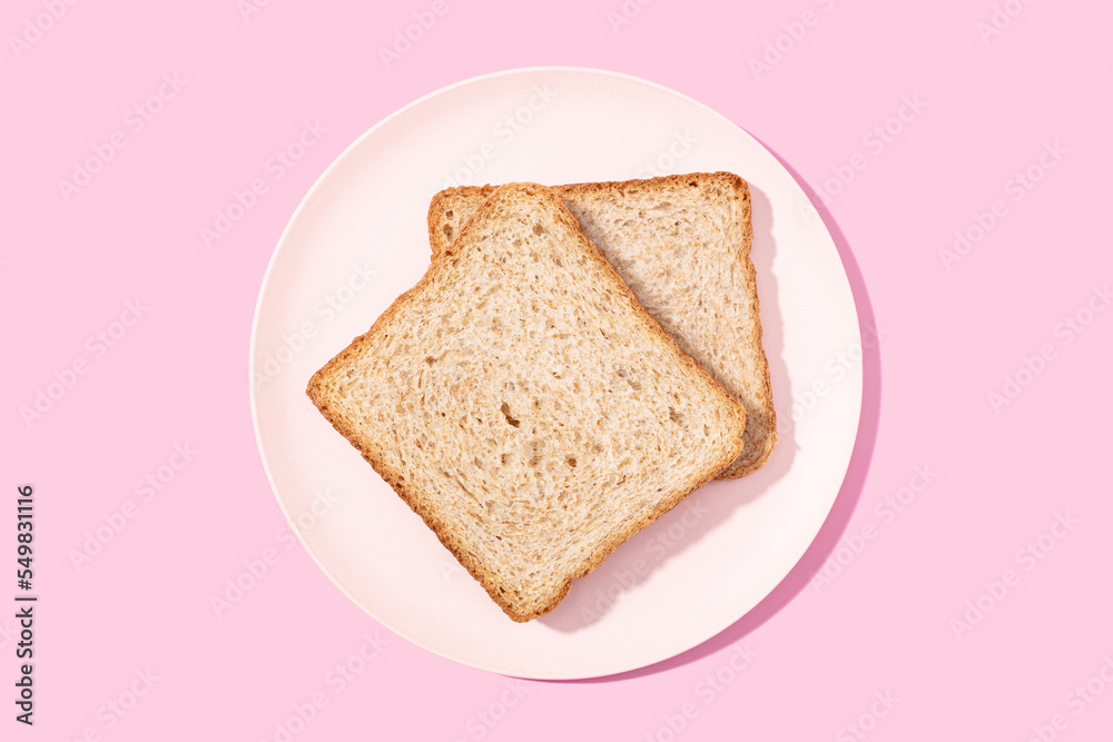 Whole wheat sandwich bread on plate on pink background. Flat lay Whole wheat sandwich bread on plate on pink background. Flat lay