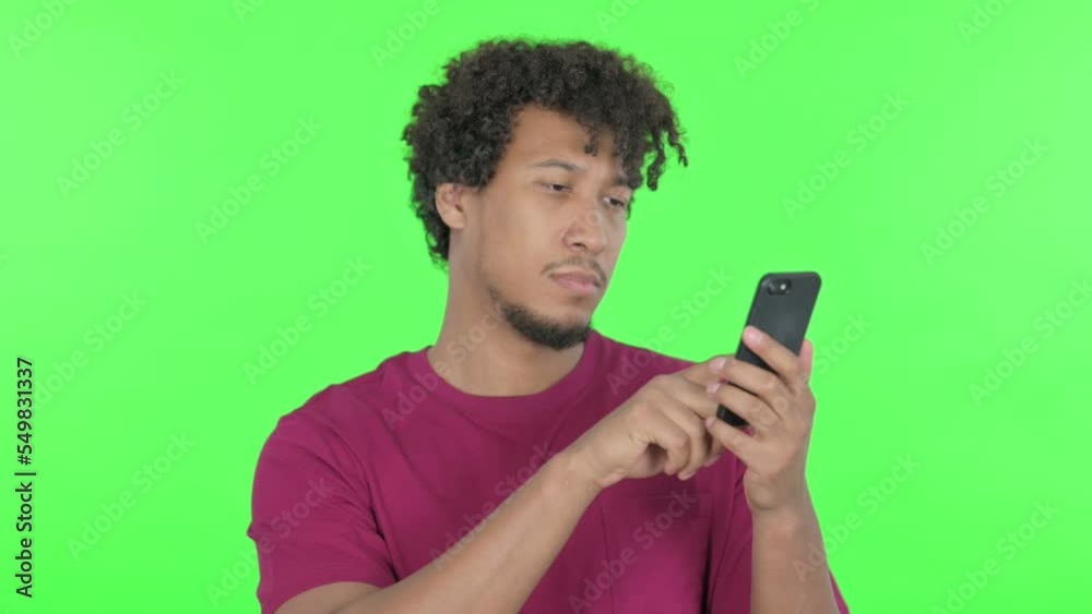 African Man Browsing Smartphone on Green Background