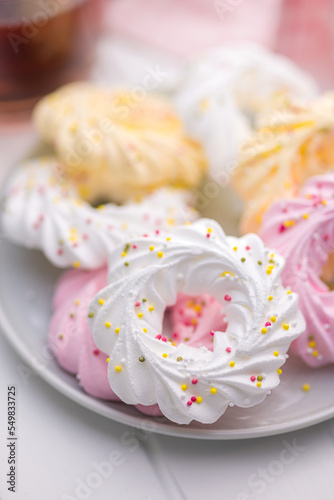 Different colors meringues with sprinkles on plate.