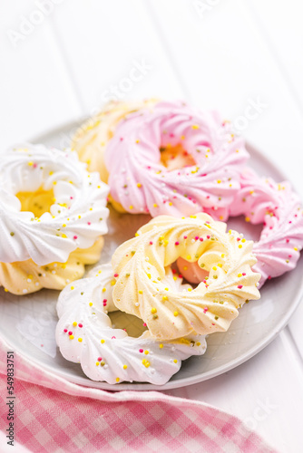 Different colors meringues with sprinkles on plate.