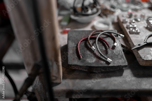 Three handmade bracelets are resting on top of the jeweler work table