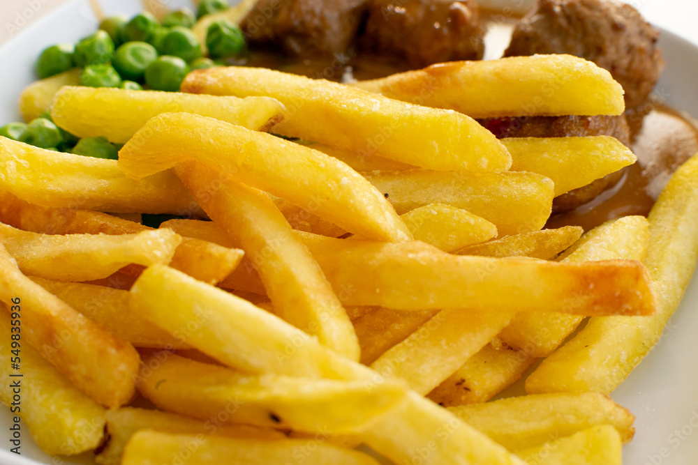 Meatballs with French Fries, Green Peas, Bechamel Sauce on White Plate Meatballs with French Fries, Green Peas, Bechamel Sauce on White Plate