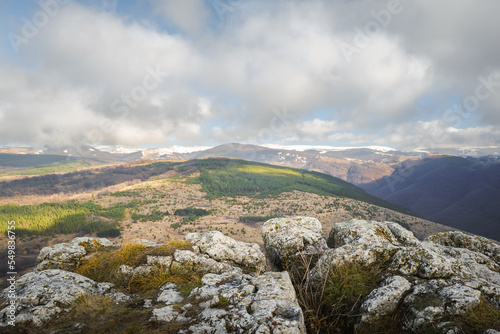Beautiful view on a distant snow covered mountains with foreground rocks and cloudy sty