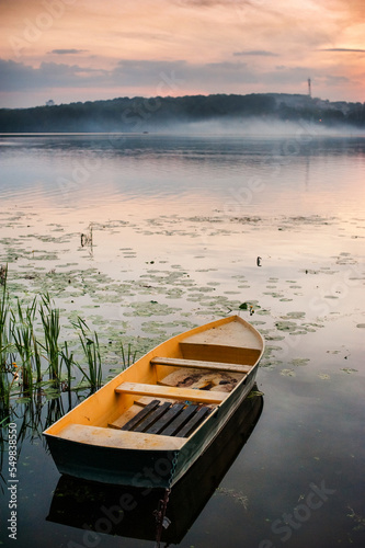 a foggy pond and a lonely boat in the foreground, an idyll of autumn