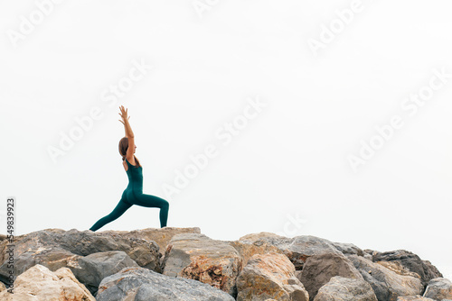 Portrait of fit woman practicing various yoga asanas  outdoors by the sea  doing crescent pose or high lunge  ashta chandrasana in nature. Energy  flexibility  strength and power concept. Copy space
