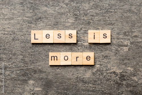 less is more word written on wood block. less is more text on table, concept