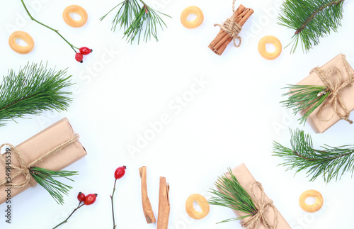 Christmas composition. Christmas gift, fir branches, bagels and cinnamon in tubules on a white background. Flat lay, top view, copy space. Happy New Year!