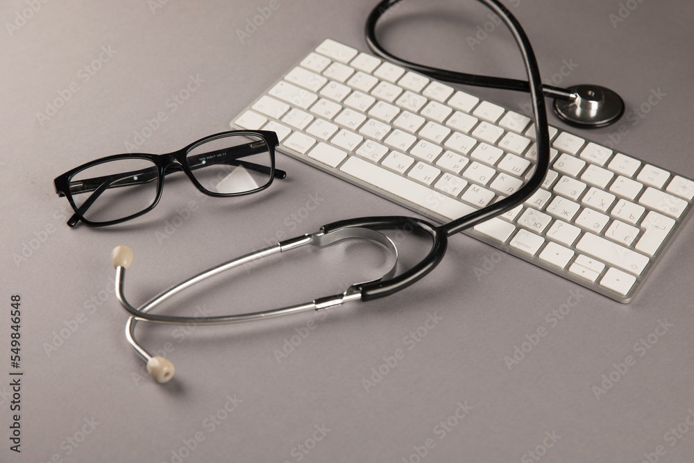 Stethoscope, glasses and keyboard on desktop Stethoscope, glasses and keyboard on desktop