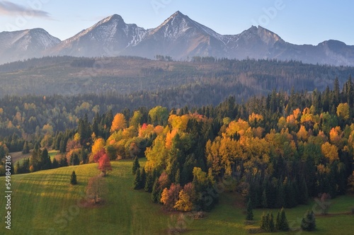 Beautiful rural mountain view. Autumn landscape with colorful trees and hills in the background. Photo taken in Osturnia village, Slovakia.