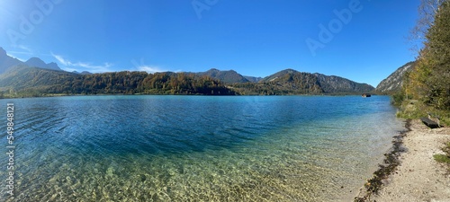 Panoramic shot of the beautiful blue lake and surrounding moutains on a sunny day © Unknown Unknown6480/Wirestock Creators
