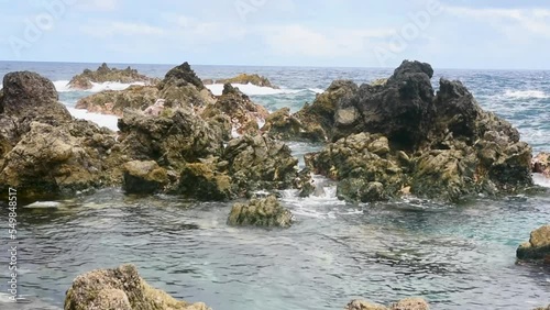 Landscape of Sea waves crashing rocky formations with blue sky photo
