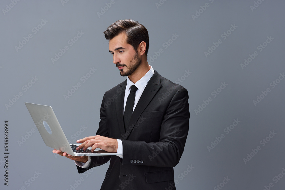 Man business looks into laptop and works online via internet in business suit video call on gray background copy space Man business looks into laptop and works online via internet in business suit video call on gray background copy space